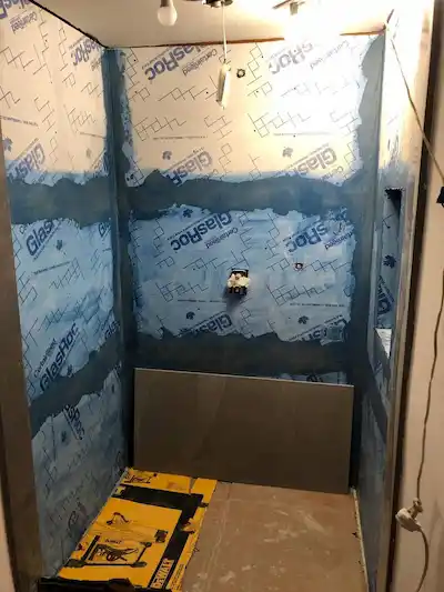 Walk-in shower renovation showing waterproof tile backer boards and sealed seams by Sharp Edge Interiors