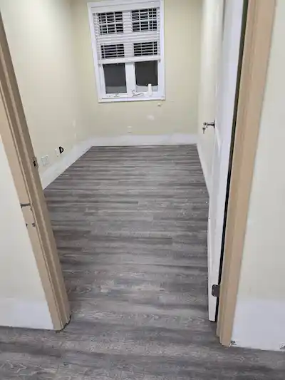 Newly installed grey wood-look laminate flooring and fresh painting in a residential room renovation